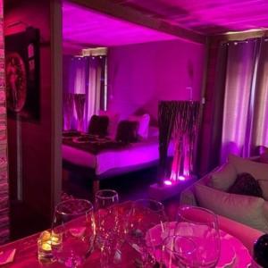 ein Raum mit violetten Lichtern und Gläsern auf einem Tisch in der Unterkunft Charme Suite - Antre-parenthèse in Gravelines