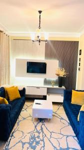 a living room with blue couches and a tv at Modest Spacious Apartment in Kampala