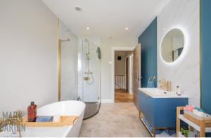 a bathroom with a tub and a shower and a sink at BridShu Den New build Townhouse in Larne +18 photos