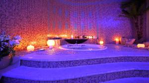 ein Badezimmer mit einer Badewanne mit Kerzen und lila Lichtern in der Unterkunft Sirena Residence & Spa in Marathokampos