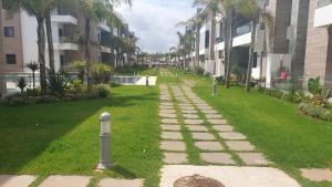 a walkway in the middle of a lawn with palm trees at Ground floor apartment - Residence Skhirat Beach 2 in Skhirat
