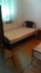 a small bed in a room with a chair at Peaceful House in Tribunj in Tribunj