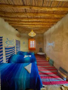 a room with three beds and a wooden ceiling at Dar Oasis Moringa in Merzane