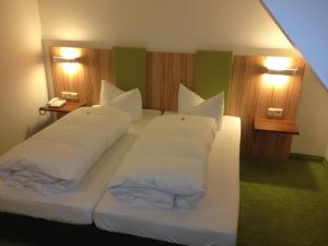 a bedroom with two beds with white pillows at Hotel am Markt in Greding