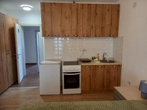 a kitchen with wooden cabinets and a white stove top oven at Apartman Ika 4N in Kraljevo