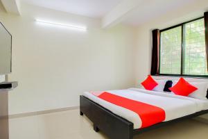 a bedroom with a bed with red and white pillows at Hotel O Galaxy Near INOX in Yeraoda +29 photos