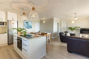 a kitchen and living room with a couch and a table at Beachfront Apartment Shakas Rock - Martinique, Pool, Ocean Views in Ballito +24 photos