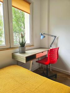a desk with a red chair next to a window at Lovely Sparkly Apartment in Krakow