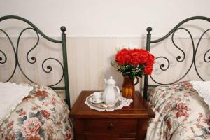 stół z wazonem róż na stole pomiędzy dwoma łóżkami w obiekcie Bed&Breakfast 1912 w mieście Fermo +30 zdjęć