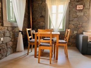 a dining room table and chairs with a stone wall at The Nomad Stone House in Kondiás