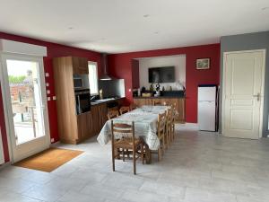 a dining room with a table and a kitchen with red walls at Gite des 3 sœurs in Vernon