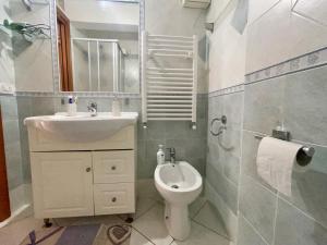 un bagno con lavandino, WC e specchio di Scalingi Family Apartments a Sperlonga