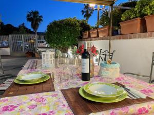 un tavolo con piatti verdi e una bottiglia di vino di Scalingi Family Apartments a Sperlonga Altre 19 foto