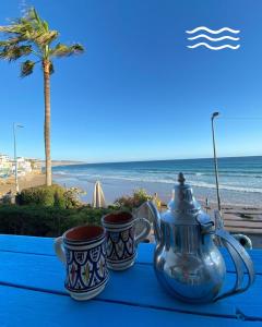 a table with two cups and a tea pot on the beach at Afoulki Home in Taghazout