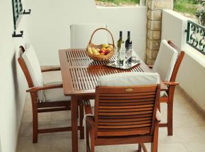 una mesa de comedor con una cesta de frutas y botellas de vino en Apartments Lancek, en Ivan Dolac