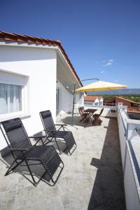 a group of chairs and an umbrella on a patio at Apartment Castelmuschio in Omišalj