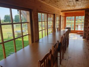 a row of tables and chairs in a room with windows at Vakarvēji in Mujani +11 photos