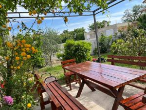 a wooden picnic table and two benches in a garden at Lutovac Apartmani in Kotor