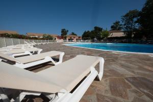 a row of white lounge chairs next to a swimming pool at Villa ALOHA pool-beach 500m in Santa-Maria-Poggio +19 photos