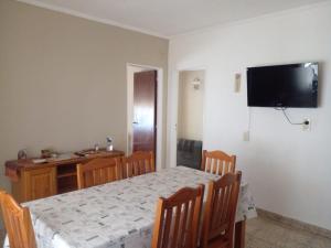 a dining room with a table and a television on the wall at LOS CACTUS in Tandil