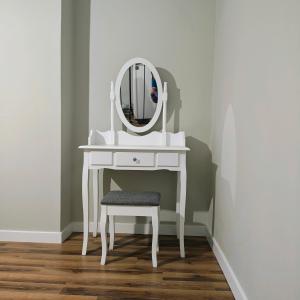 a white dressing table with a mirror and a stool at Apartament Pomarańczowy Gdańsk 80 metrów z widokiem na ogród in Gdańsk
