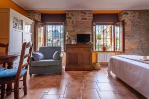 a bedroom with a bed and a chair and a television at Apartamentos El Cruce de Moratón in Cóbreces