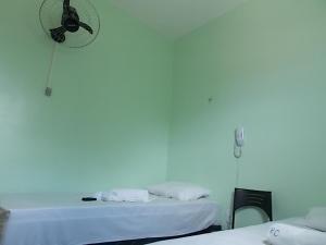 Habitación blanca con 2 camas y reloj en la pared en Pousada Cariri en Juazeiro do Norte