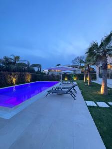 a patio with a table and a pool at night at San Pietro Villa 7 in Draçi