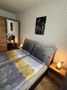 a bed in a bedroom with a white brick wall at VITRUVIAN Apartament 13 - Self check in 24h in Reşiţa