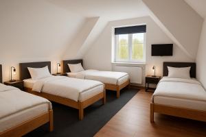 a attic room with three beds and a tv at Pension Bockenem in Bockenem
