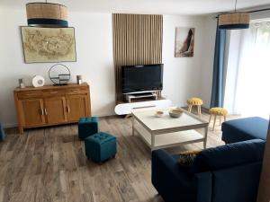 ein Wohnzimmer mit einer blauen Couch und einem Fernseher in der Unterkunft Villa La Glycine in Saint-Avé