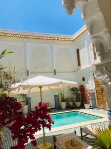 a house with a swimming pool and an umbrella at Riad Tamazigh in Marrakech