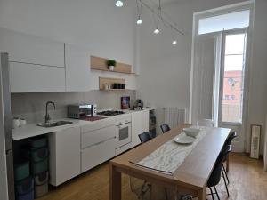 eine weiße Küche mit einem Holztisch und einem Esszimmer in der Unterkunft Madama in Bari