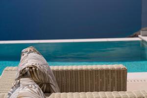 a persons legs sitting on a wicker chair next to a swimming pool at Tsimaras Villa II in Kefallonia