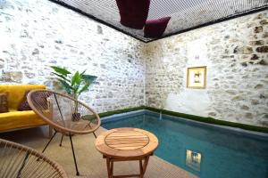 a room with a pool with chairs and a couch at La Closerie de bourdic Uzès in Bourdic