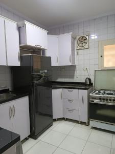 eine Küche mit weißen Schränken und einem schwarzen Kühlschrank in der Unterkunft مستقبل للشقق الفندقيه والالعاب المائيه in El-Alamein