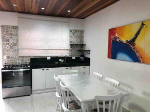 a kitchen with a white table and white chairs at Apartamento Duplex em Juquehy in São Sebastião