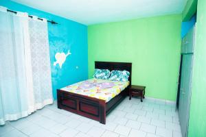 een slaapkamer met een bed in een kamer met groene muren bij Crystal Home in Douala