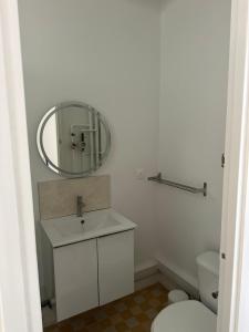 a white bathroom with a sink and a mirror at france paris in Montrouge