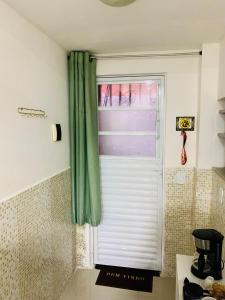una finestra con una tenda verde in una cucina di Studio em vila a 100m praia do recreio a Rio de Janeiro