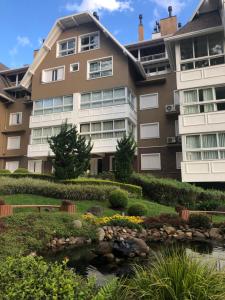 un edificio de apartamentos con un estanque delante en Altos da Bela Vista, en Gramado