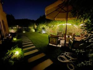 a garden at night with an umbrella and chairs at Amazing 3br Villa in Emaar - Mivida in New cairo