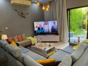 a living room with a couch and a flat screen tv at Amazing 3br Villa in Emaar - Mivida in New cairo