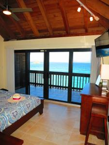 a bedroom with a bed and a desk with a view of the ocean at 2BR Luxury Beachfront Duplex Villa on Sapphire Beach III in East End