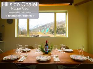 a table with glasses and a bottle of wine on it at Morino Chalets in Hakuba