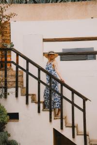 Una mujer con vestido y sombrero parada en las escaleras. en Argentiera HollyHouse, en Miniera dellʼArgentiera