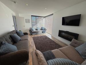Una sala de estar con dos sofás y un televisor de pantalla plana. en Detached Modern Home Portstewart, en Portstewart