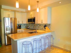 a kitchen with a sink and four bar stools at 2BR Luxury Beachfront Duplex Villa on Sapphire Beach III in East End