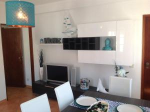 a dining room with a table and chairs and a television at Casa do Mar in Sesimbra