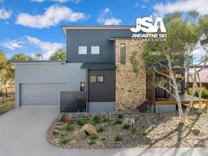 a house with a garage in a yard at Stone and Crow in Jindabyne